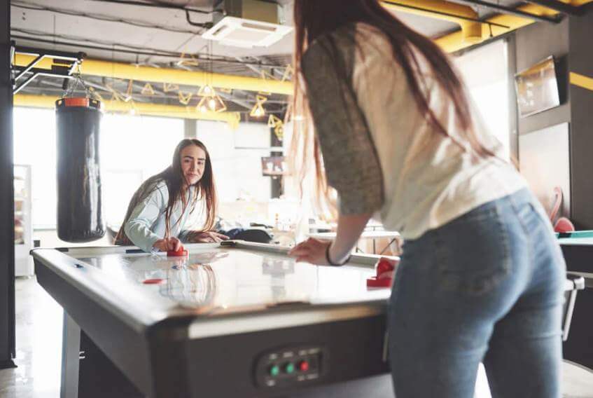 two girls playing air hockey