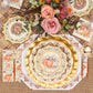 A fall-themed table setting features the Turkey & Gourds Table Setting Bundle by Sophistiplate LLC, including designer disposable plates adorned with turkey and gourd motifs, gold cutlery, plaid and burlap placemats, and a floral centerpiece with pink roses and autumnal blooms. The distinctive turkey design appears on both the top plate and matching napkin.